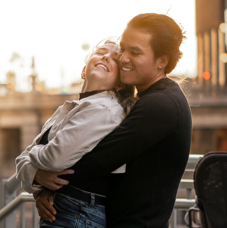 Engagement shoot of a man holding and spinning a woman, Both smiling, Background is Chicago skyline