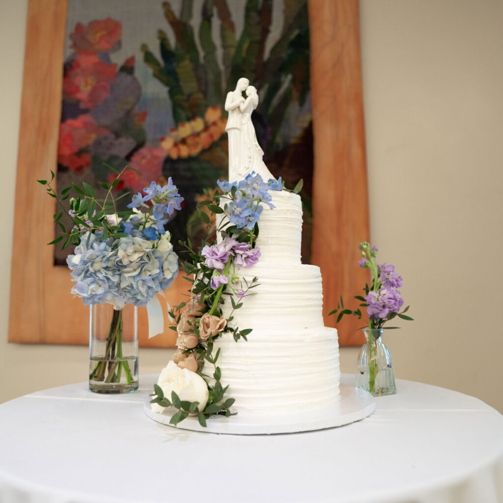 three tier wedding cake with blue and purple flowers at desert botanical garden in arizona