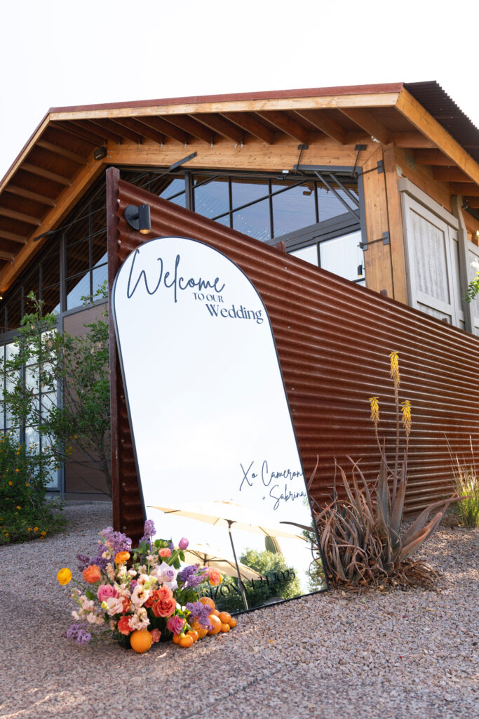 Welcome mirror sign with black decals and color flowers at the Paseo