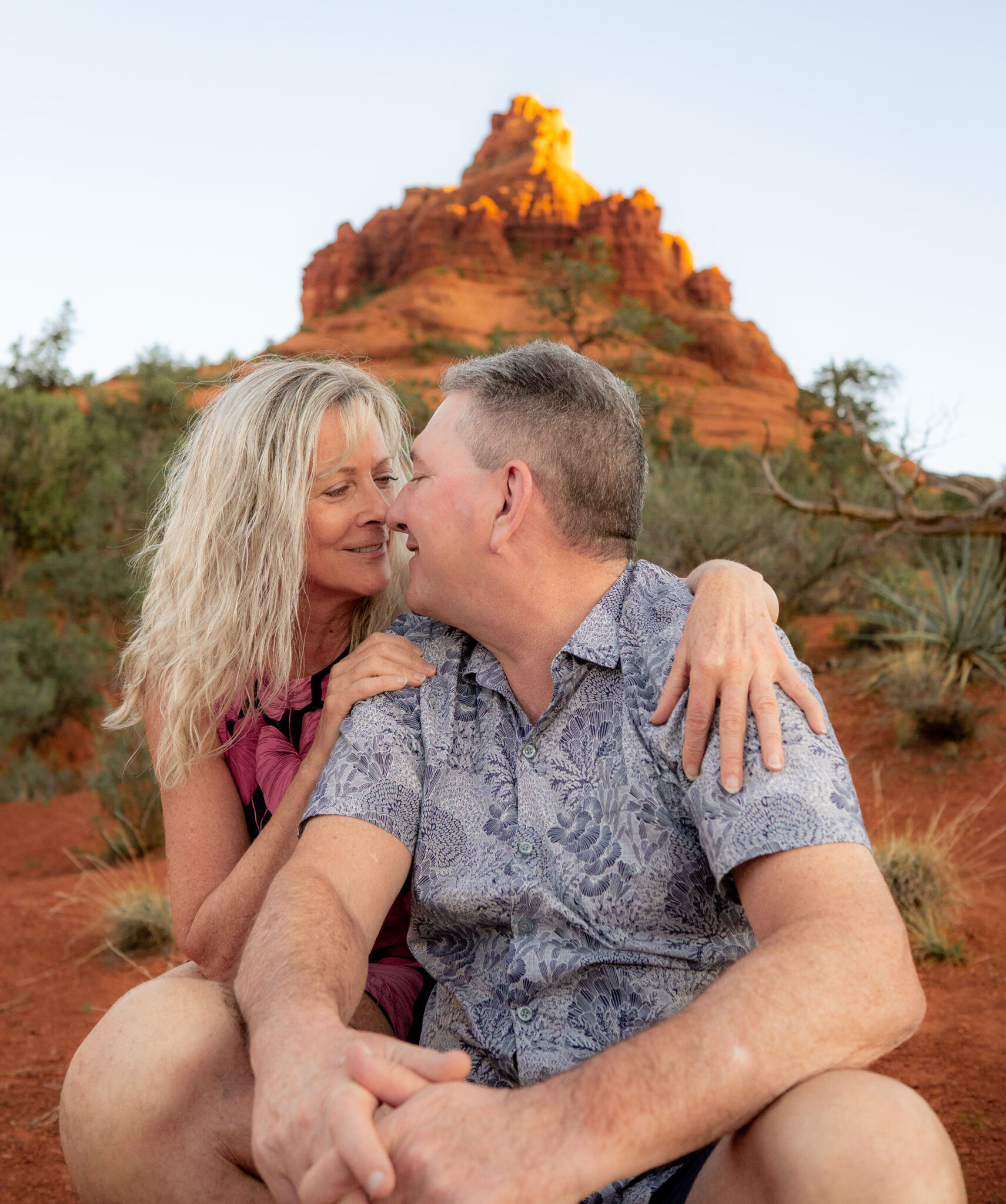 Male and female couple smiling and kissing with Sedona red rocks in the background