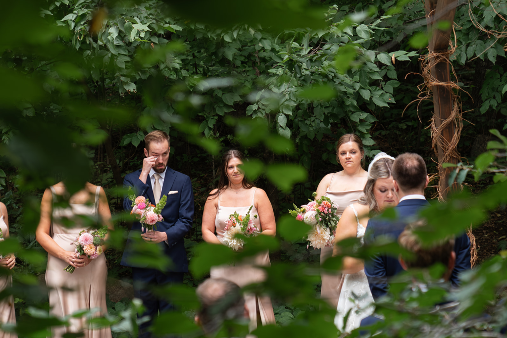 groomsmen crying at wedding ceremony in the woods