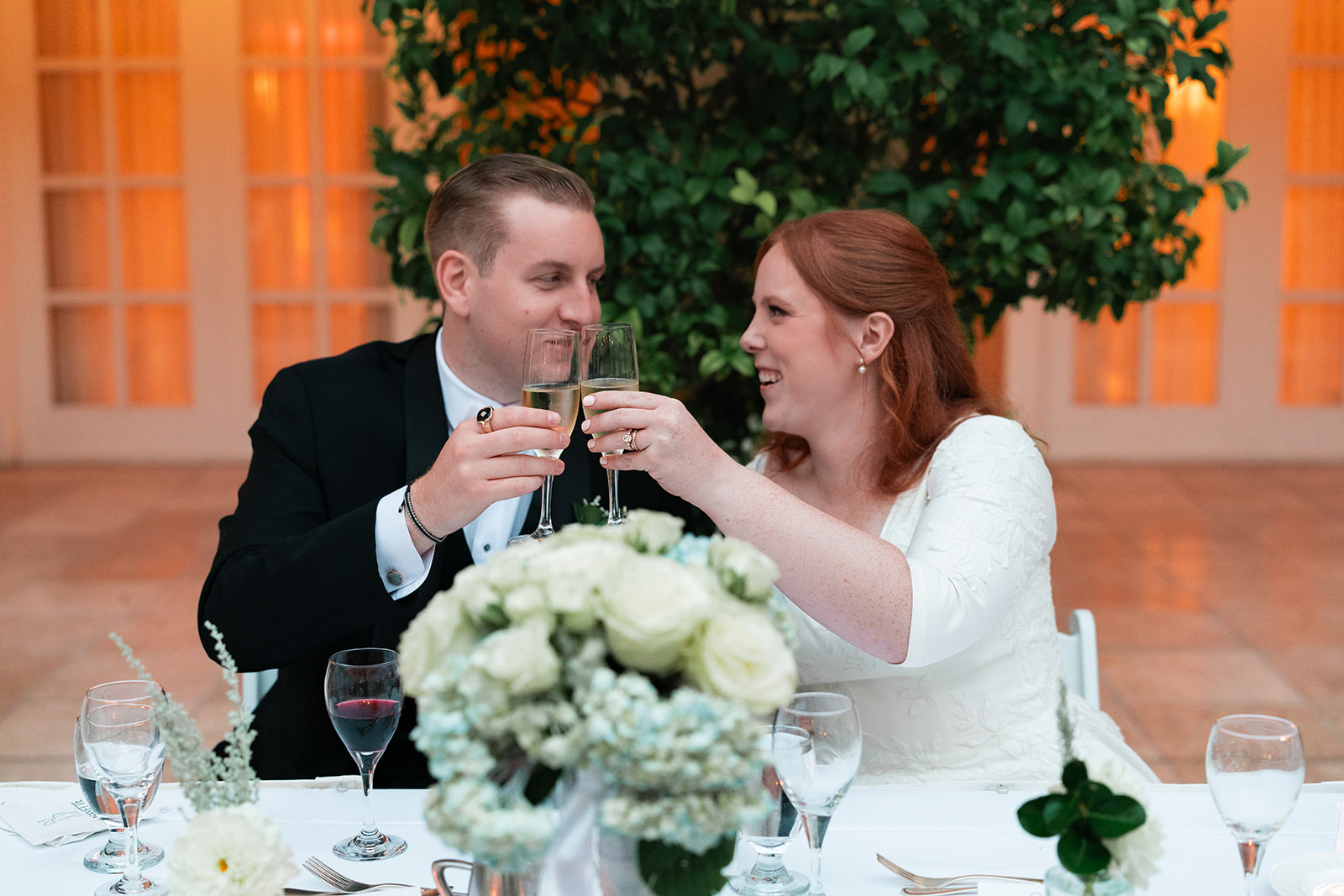 bride and groom clinking glasses at their sweetheart table during their wedding reception at the courtyard at the lafayette park hotel