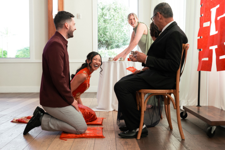 bride smiling while offering tea to her parents during a chinese tea ceremony