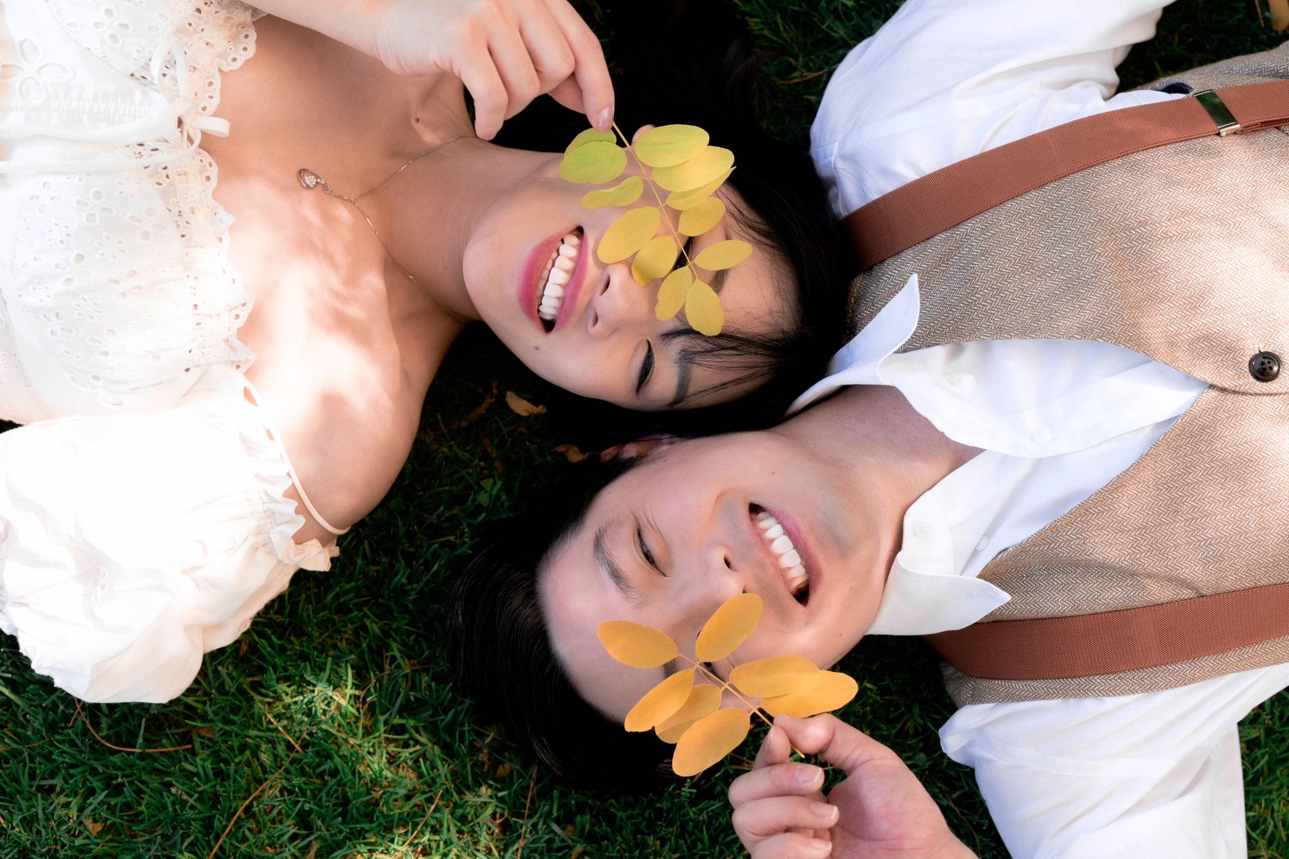 couple laying down on grass with yellow leaves at filoli gardens