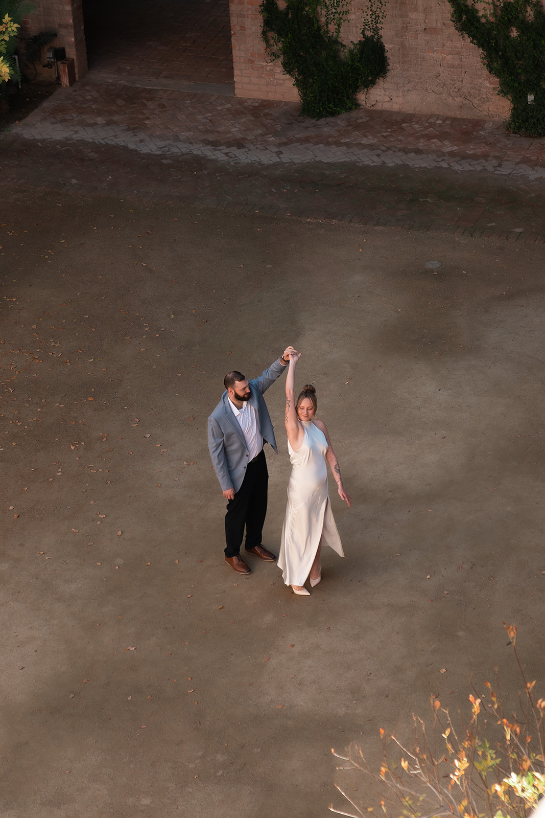 Man twirling woman in a white dress. This was taken during an engagement shoot at Monroe Street Abbey in Phoenix
