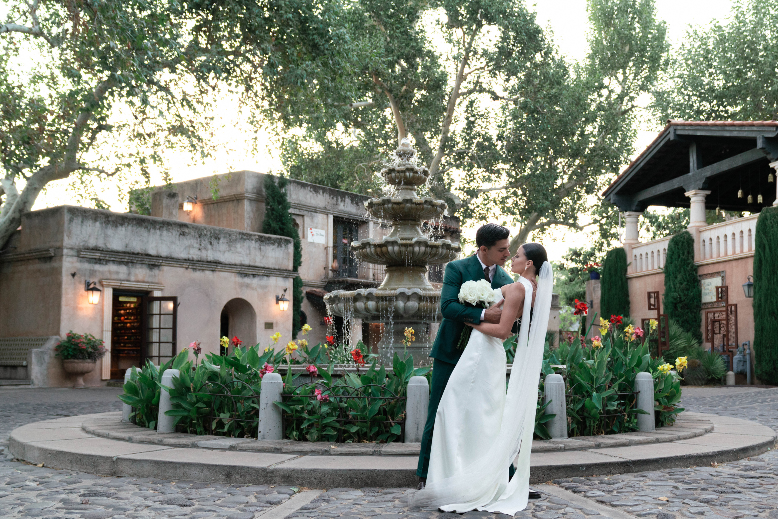 Bride and groom kissing in front of Tlaquepaque village water fountain that's multi-tiered, Spanish-colonial style stone and tile in Sedona, AZ